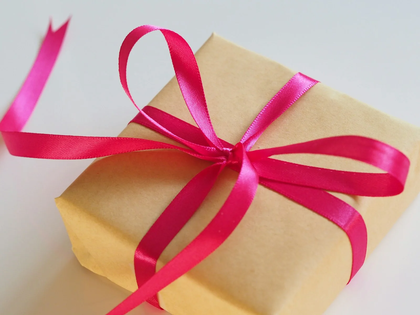 Brown paper gift wrapped with a pink ribbon.