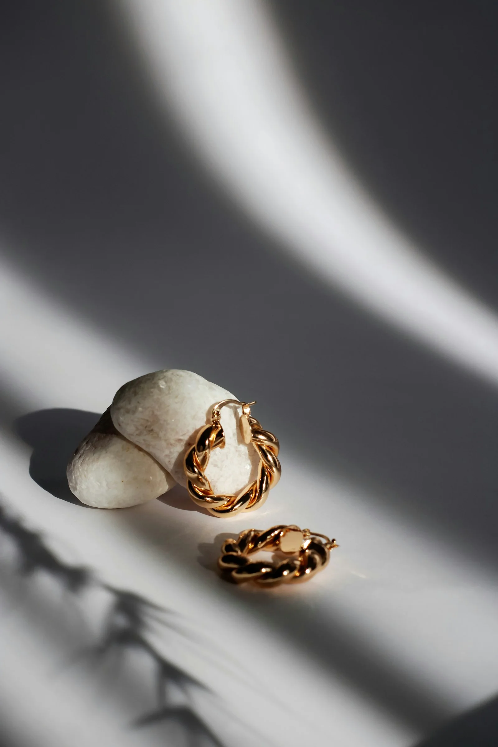 Gold-coloured jewellery arranged in a patch of sunlight.