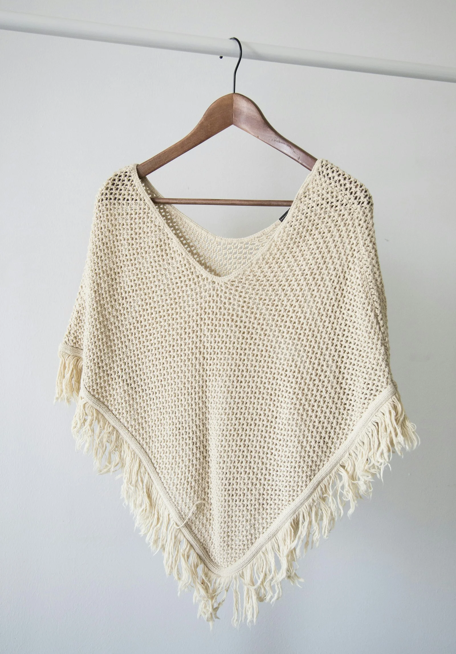 Cream knitted garment on a wooden hanger.