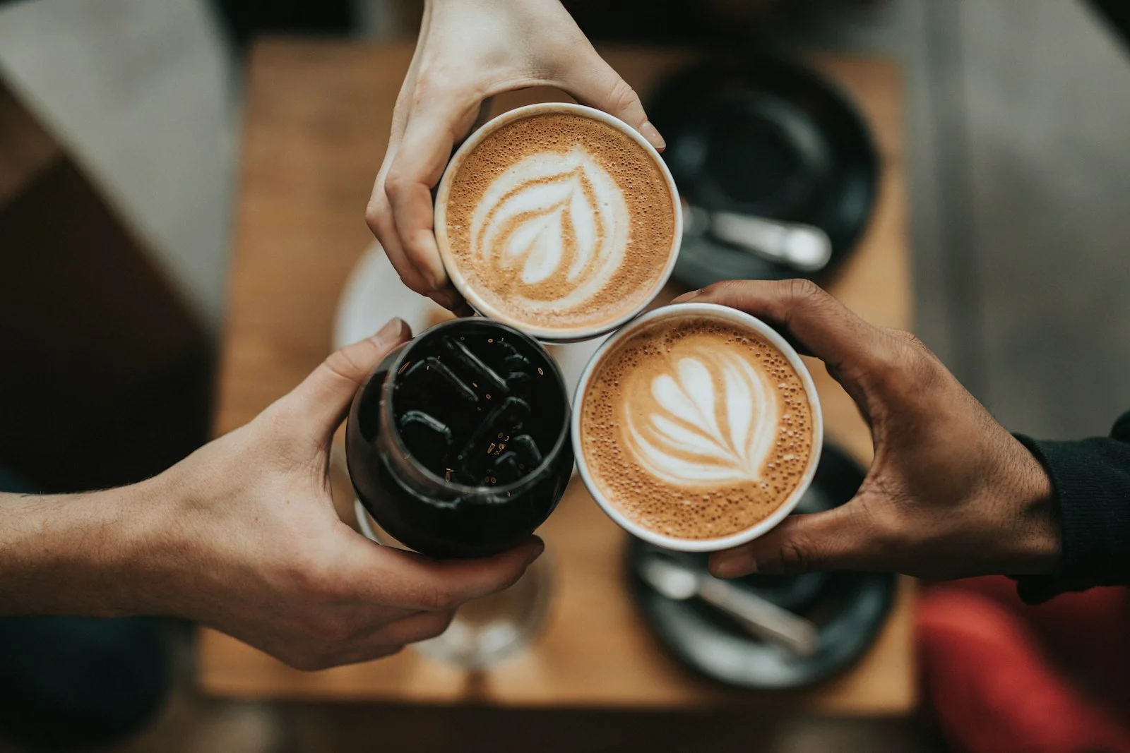 Three cups of coffee held together at a table.
