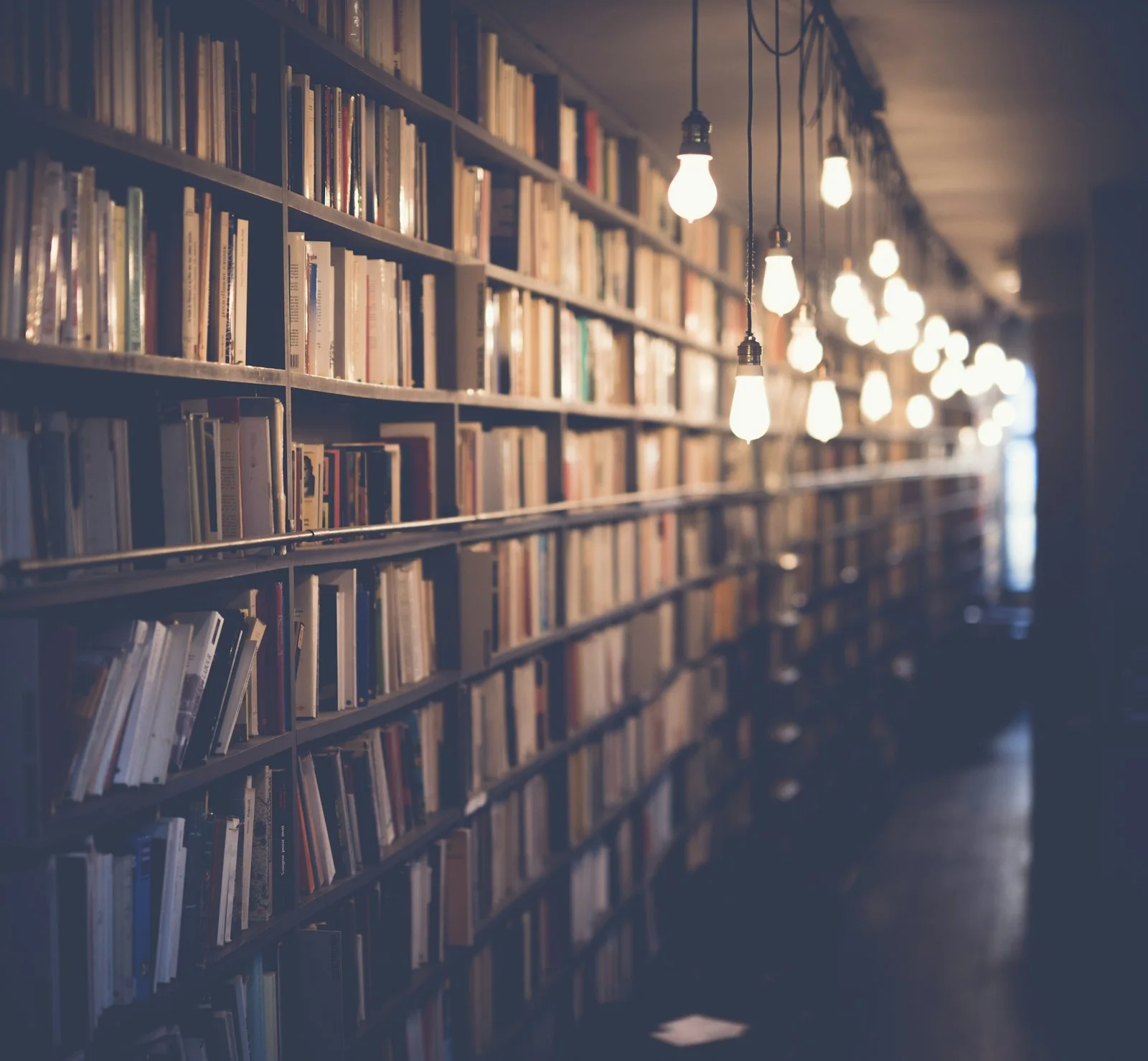 Warm lights beside library bookshelves.