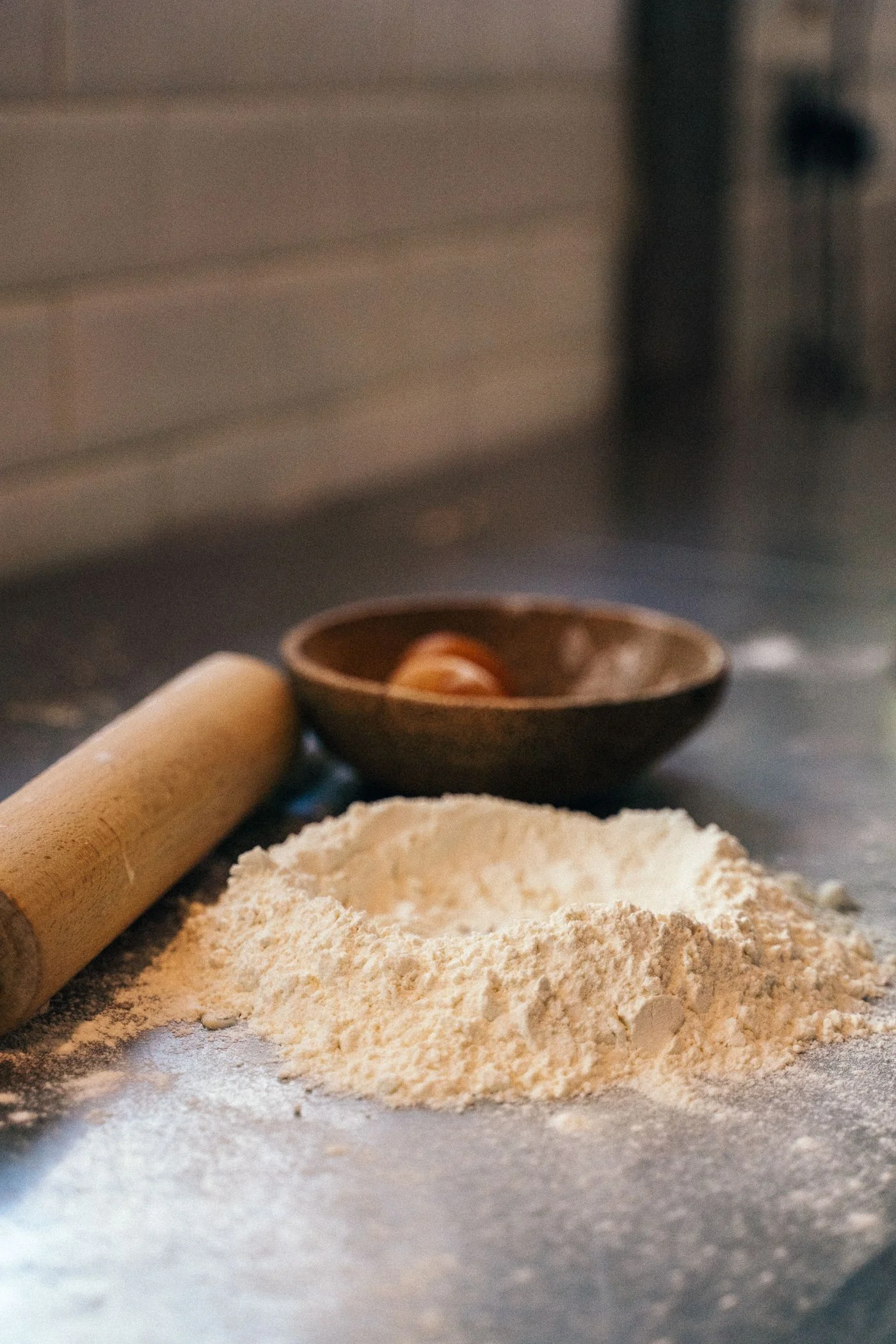 Flour and a rolling pin beside a bowl on a kitchen surface