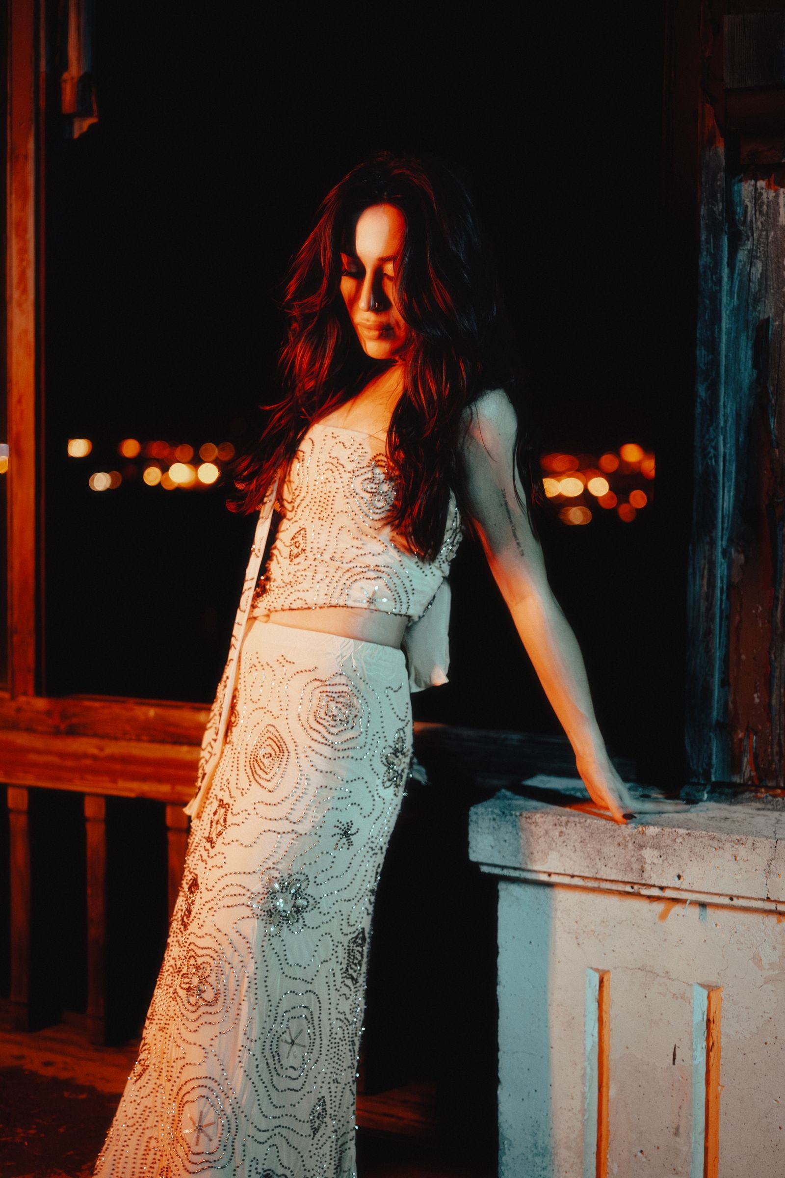 Woman wearing a patterned evening dress beside a balcony at night