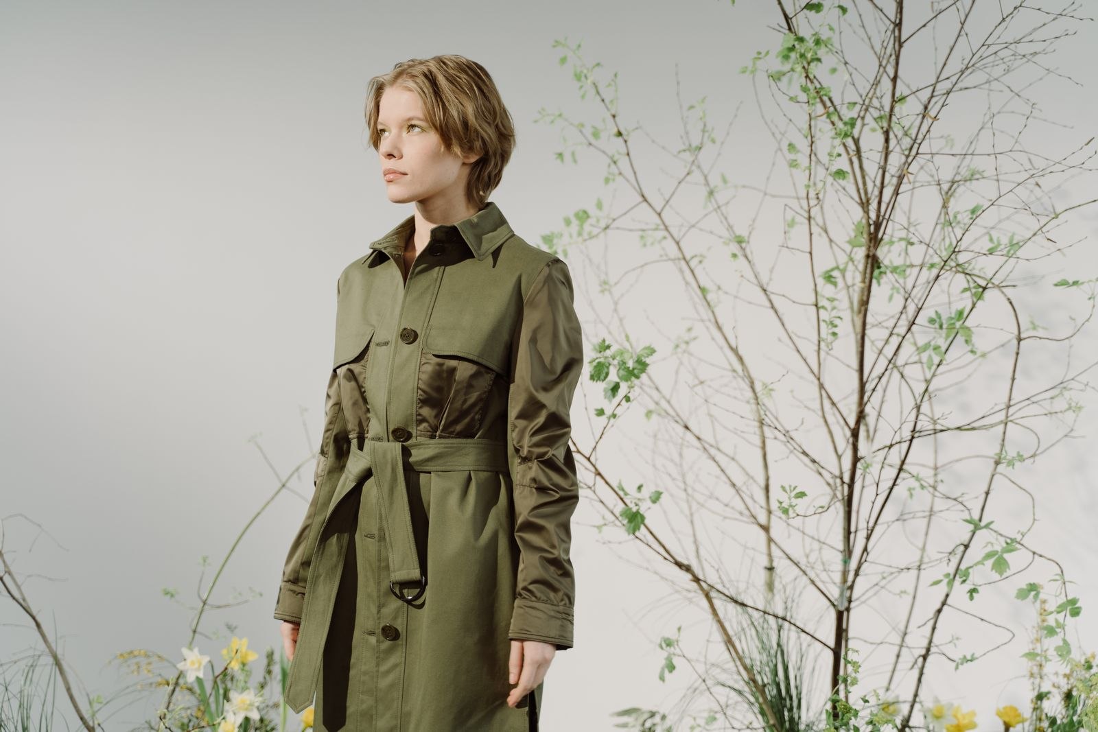 Woman wearing a green coat beside plants