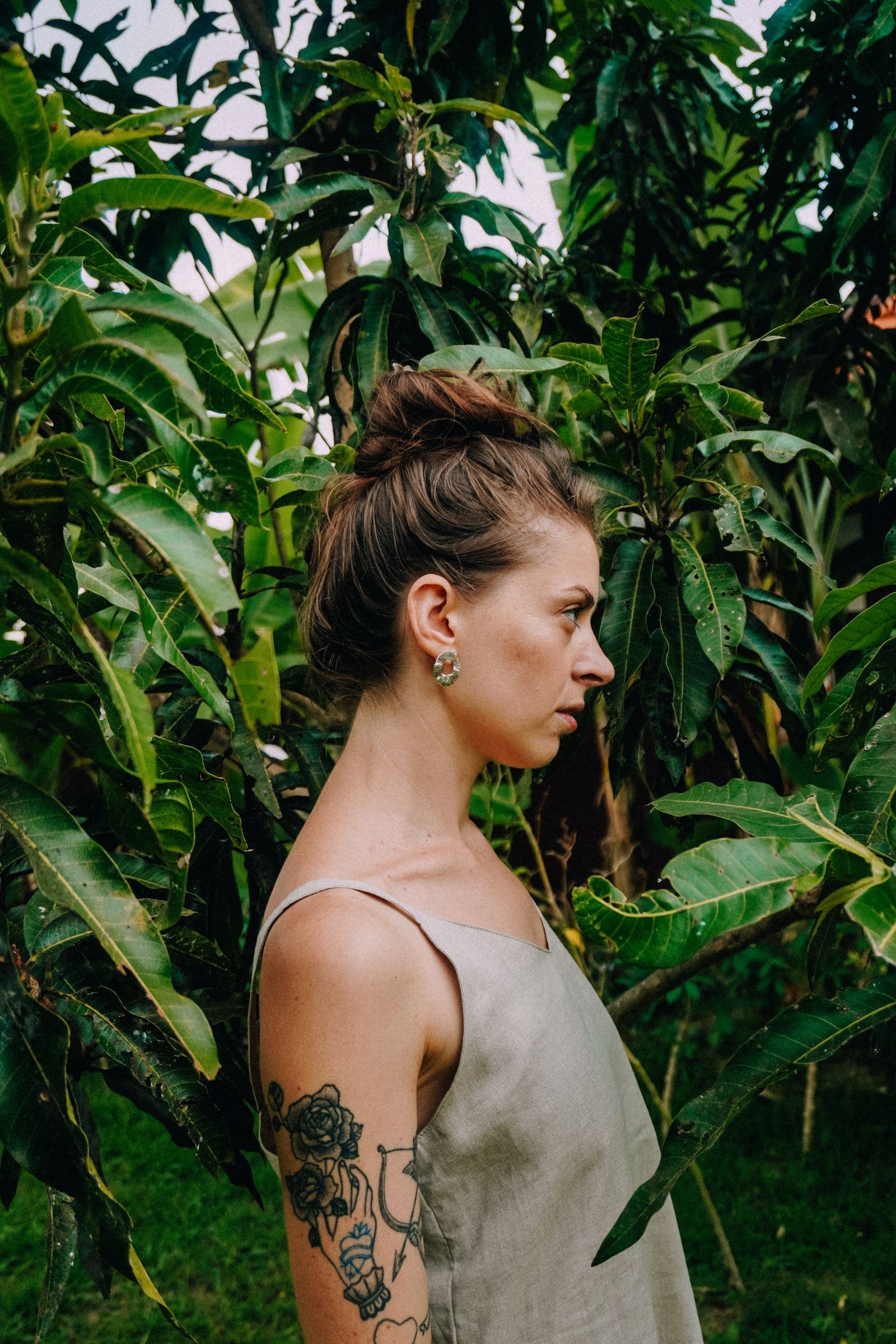 A woman in profile beside green foliage