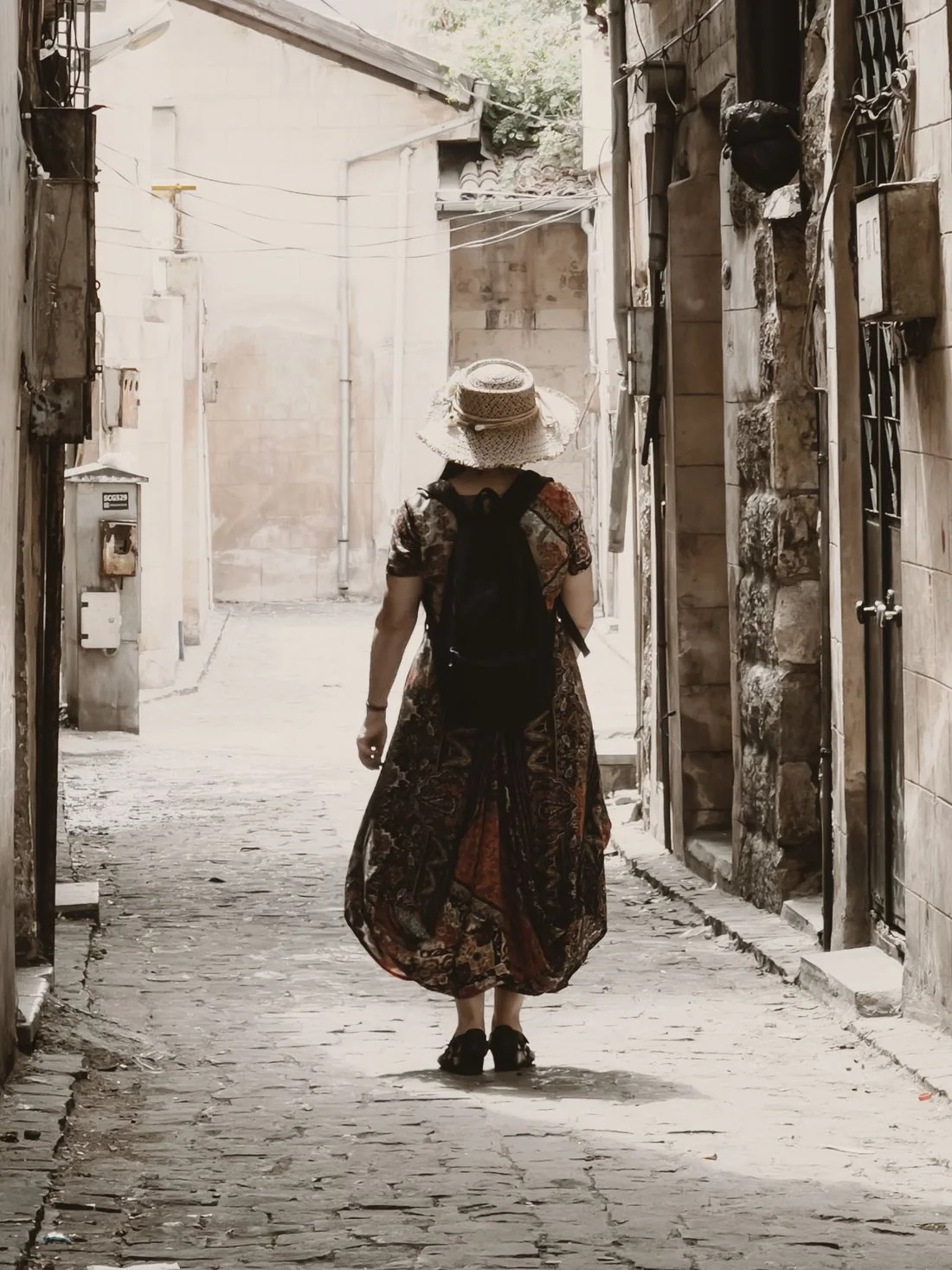 Woman in a floral maxi dress walking along an old cobblestone street