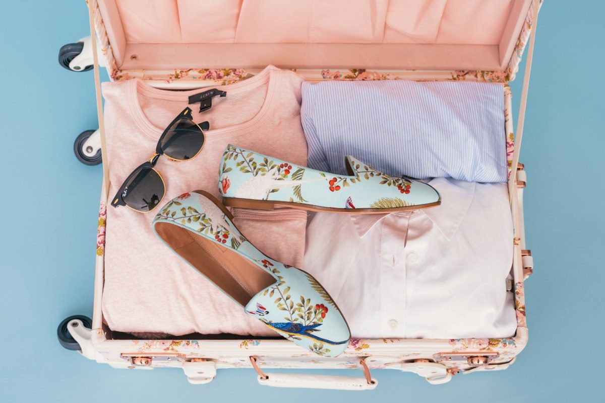 Open suitcase packed with clothing, shoes and travel accessories