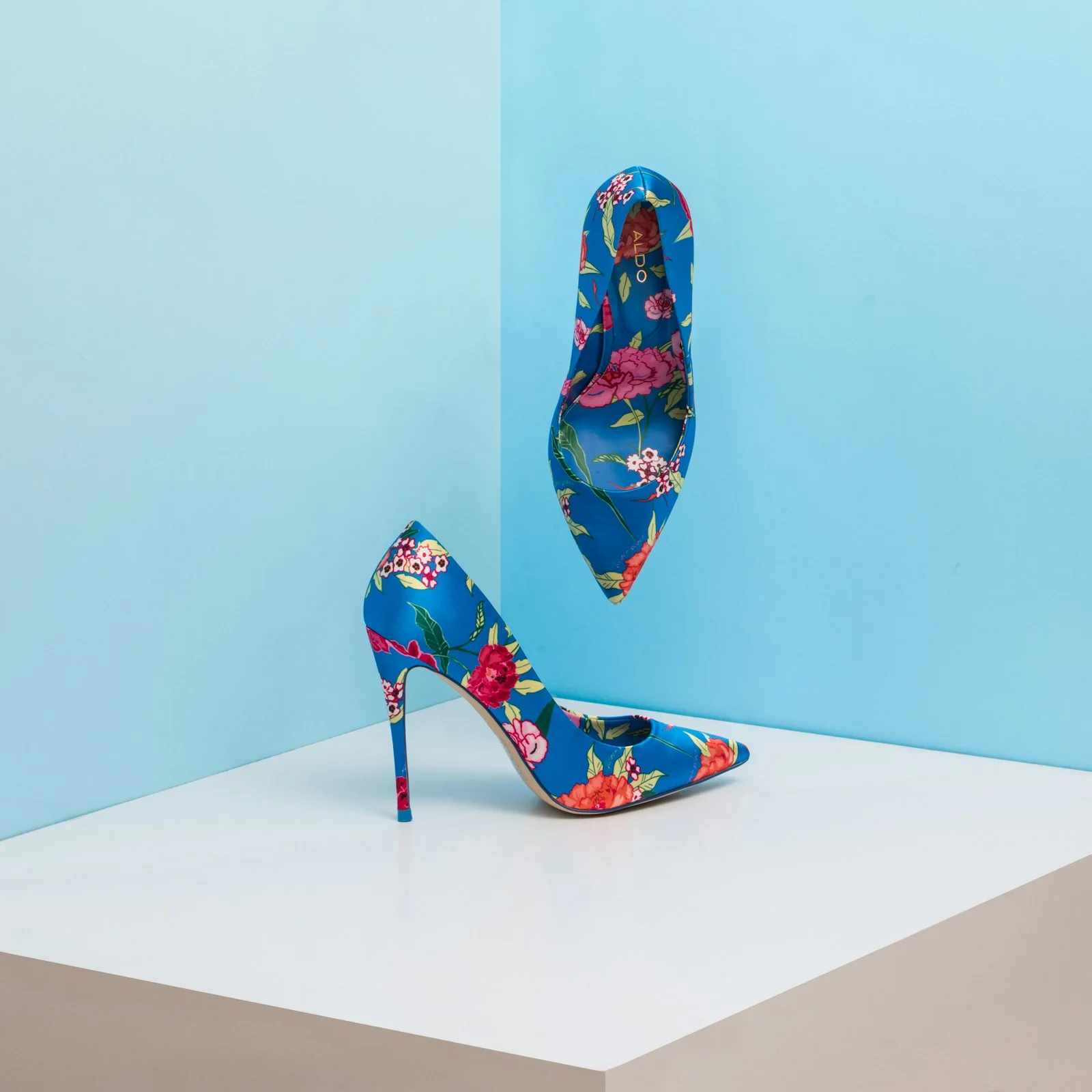 Colourful floral high-heeled shoes on display blocks.