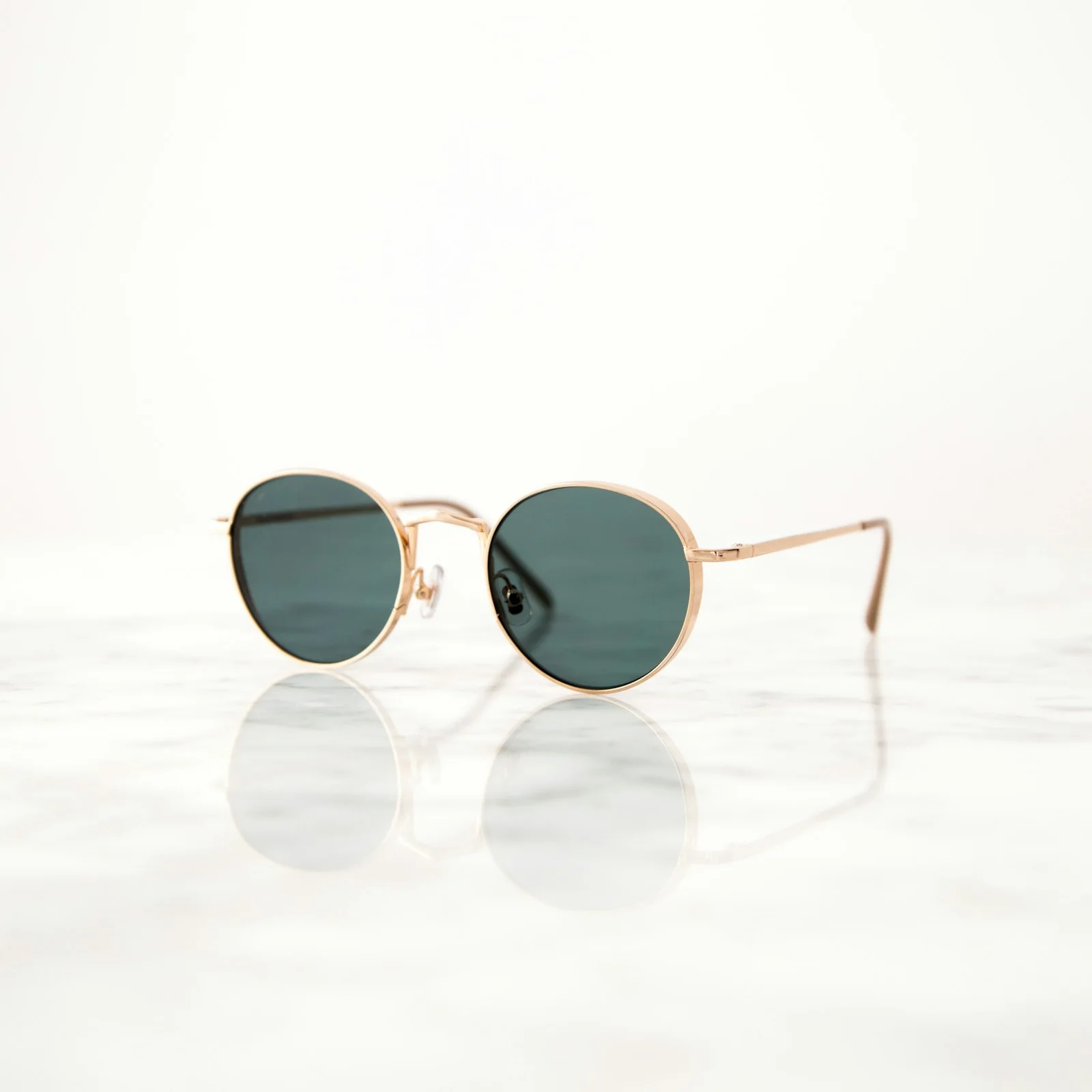 Round sunglasses with dark lenses on a pale surface.
