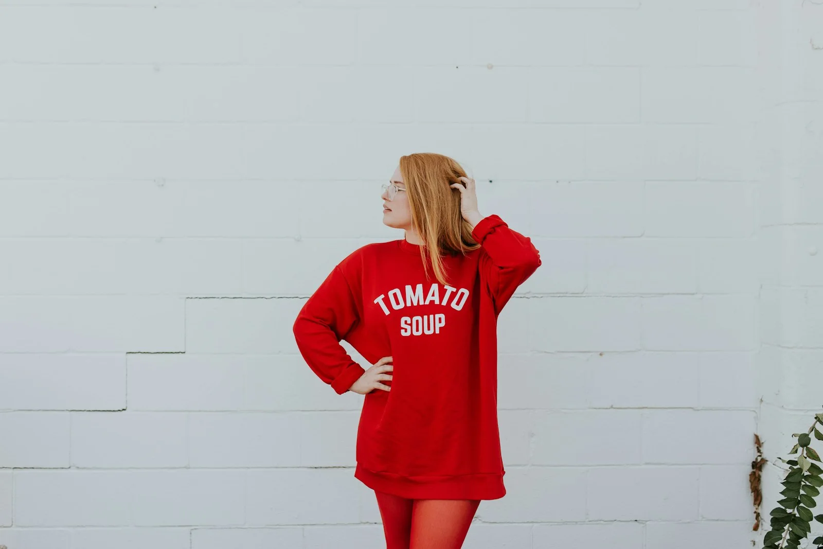Woman wearing a relaxed red outfit against a plain wall.