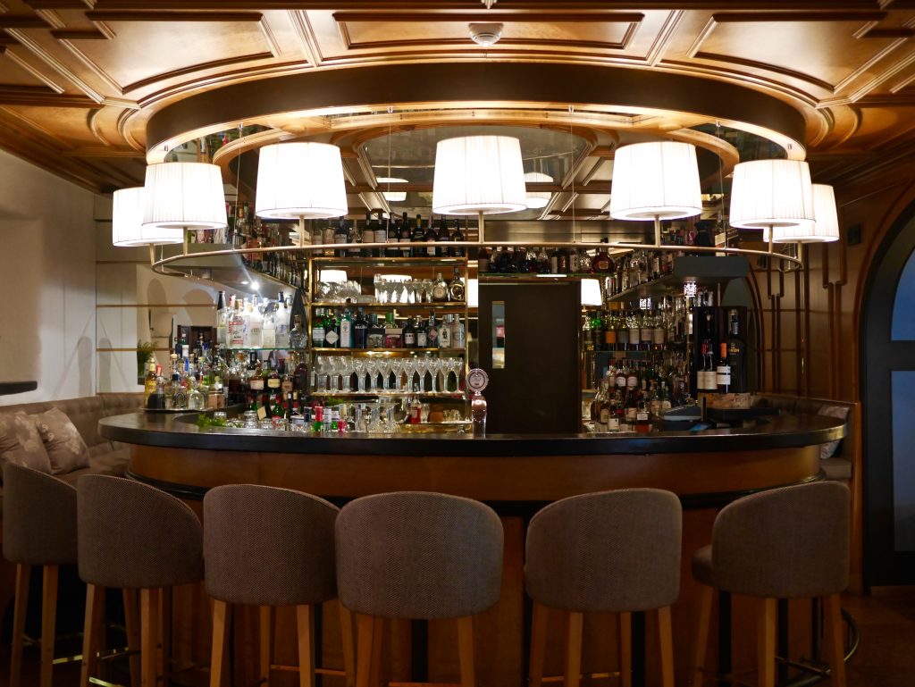 view inside the half circle piano bar surrounded by bar stools, lights and liquor/alcohol