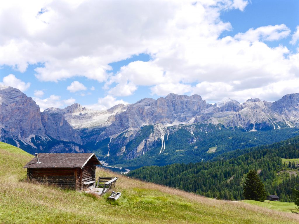 view of a wooden hut in the grassed mountains of the dolomites