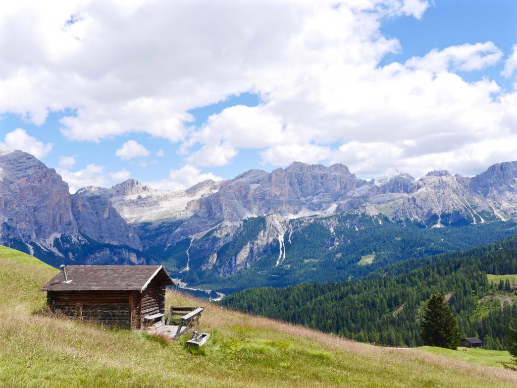 view of a wooden hut in the grassed mountains of the dolomites