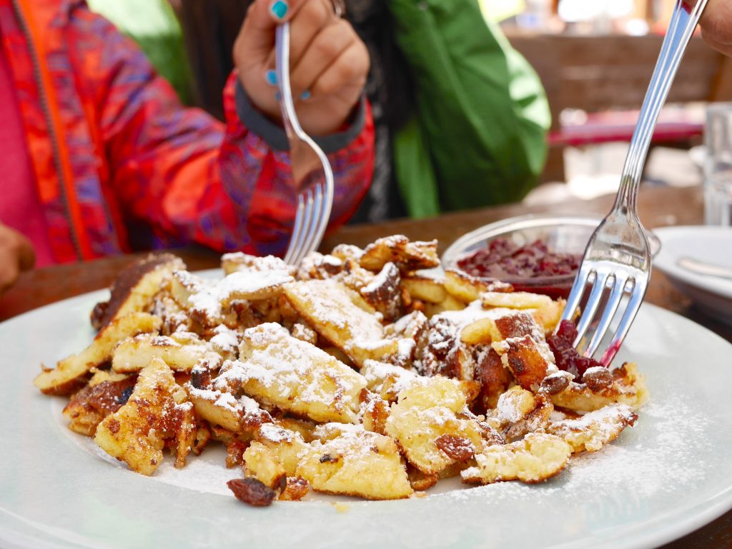 plate of Kaiserschmarren with two forks and plum compote in a glass bowl on the site