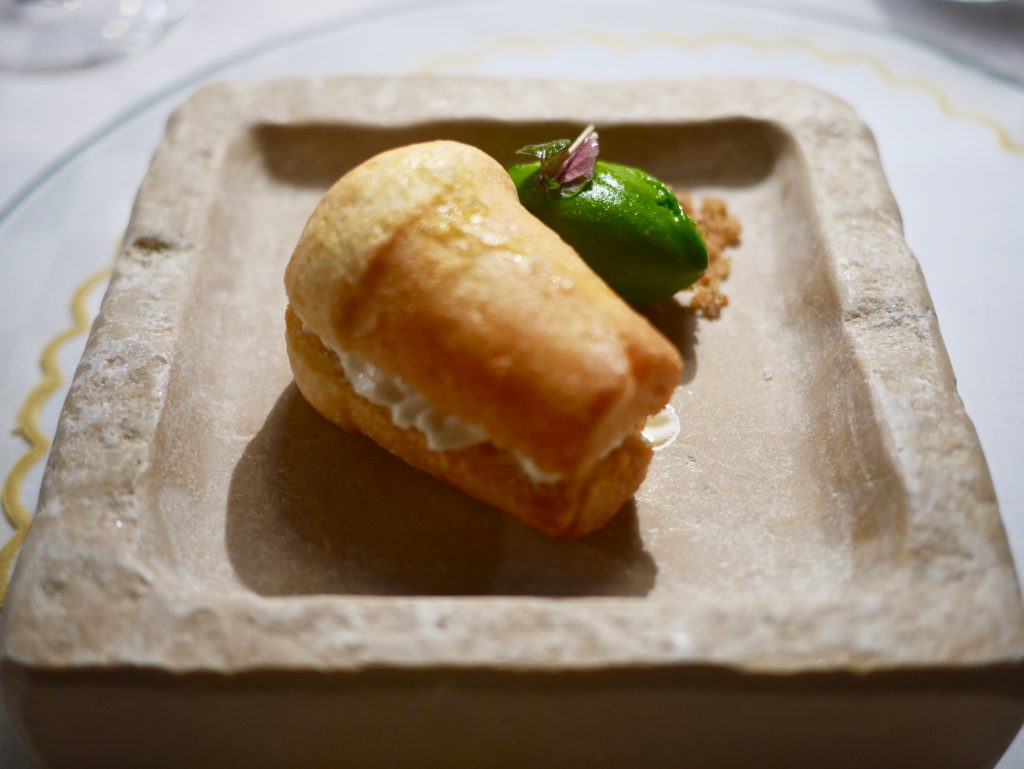 spongy cake on a stone square plate filled with stracciatella soaked in tomato water with a refreshing basil sorbet