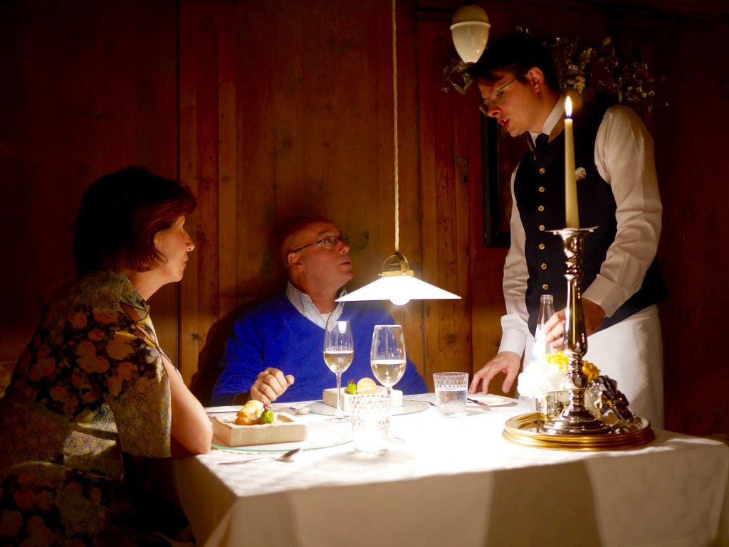server at the table of a couple in a blue jumper with low light and candle