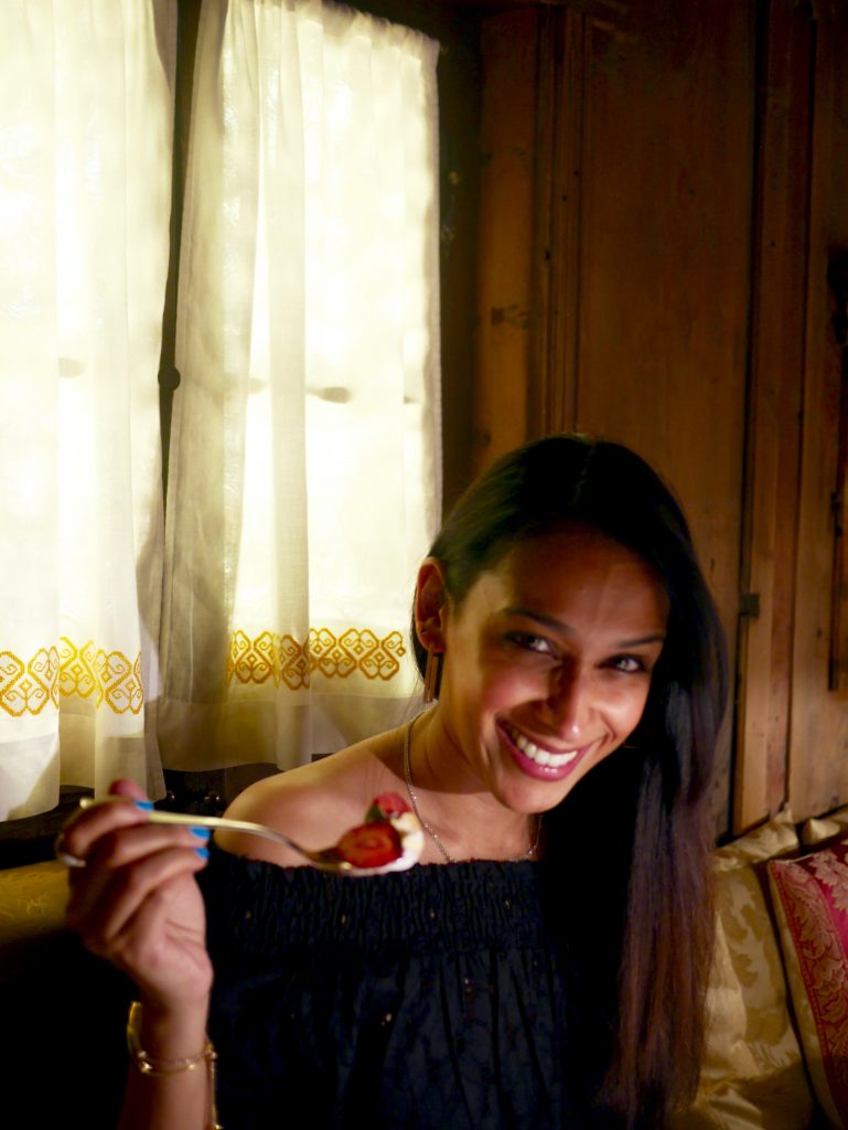 picture of sima holding strawberry dessert on a spoon smiling at the camera