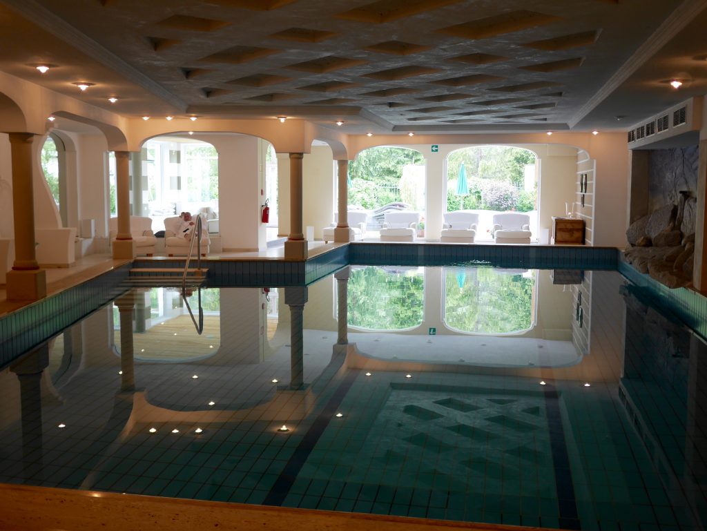 Indoor heated pool sounded by white chairs at the Rosa Alpina