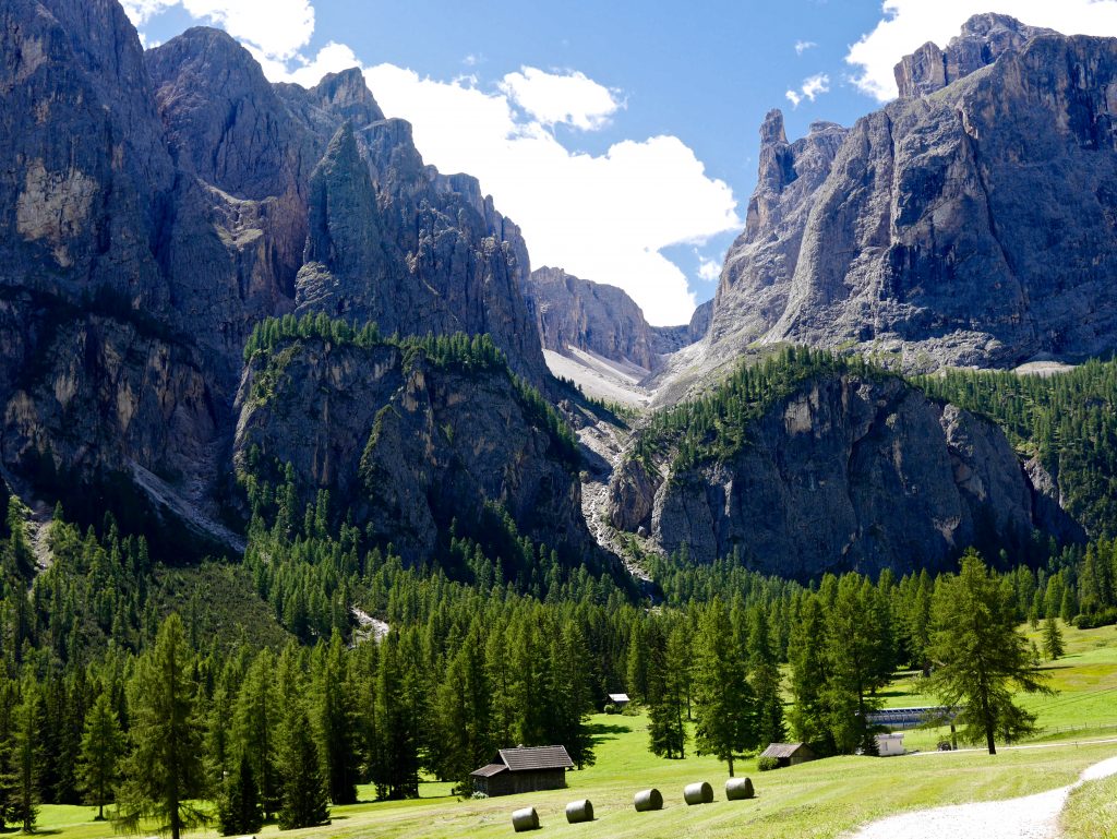 looking towards the pisciadu waterfalls valley surrounded by pine trees and small wooden huts