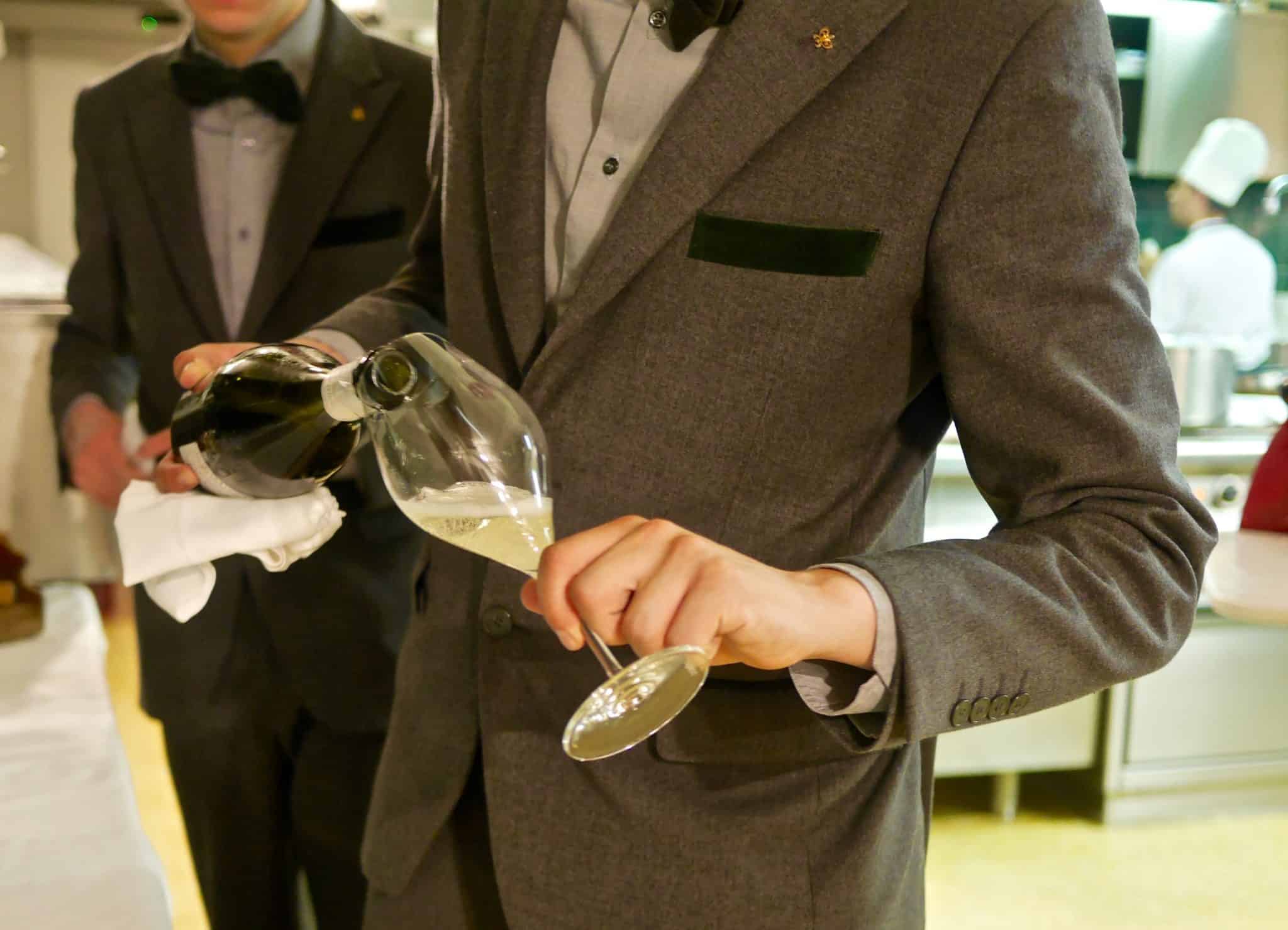 gentleman in a suite pouring white wine in a glass