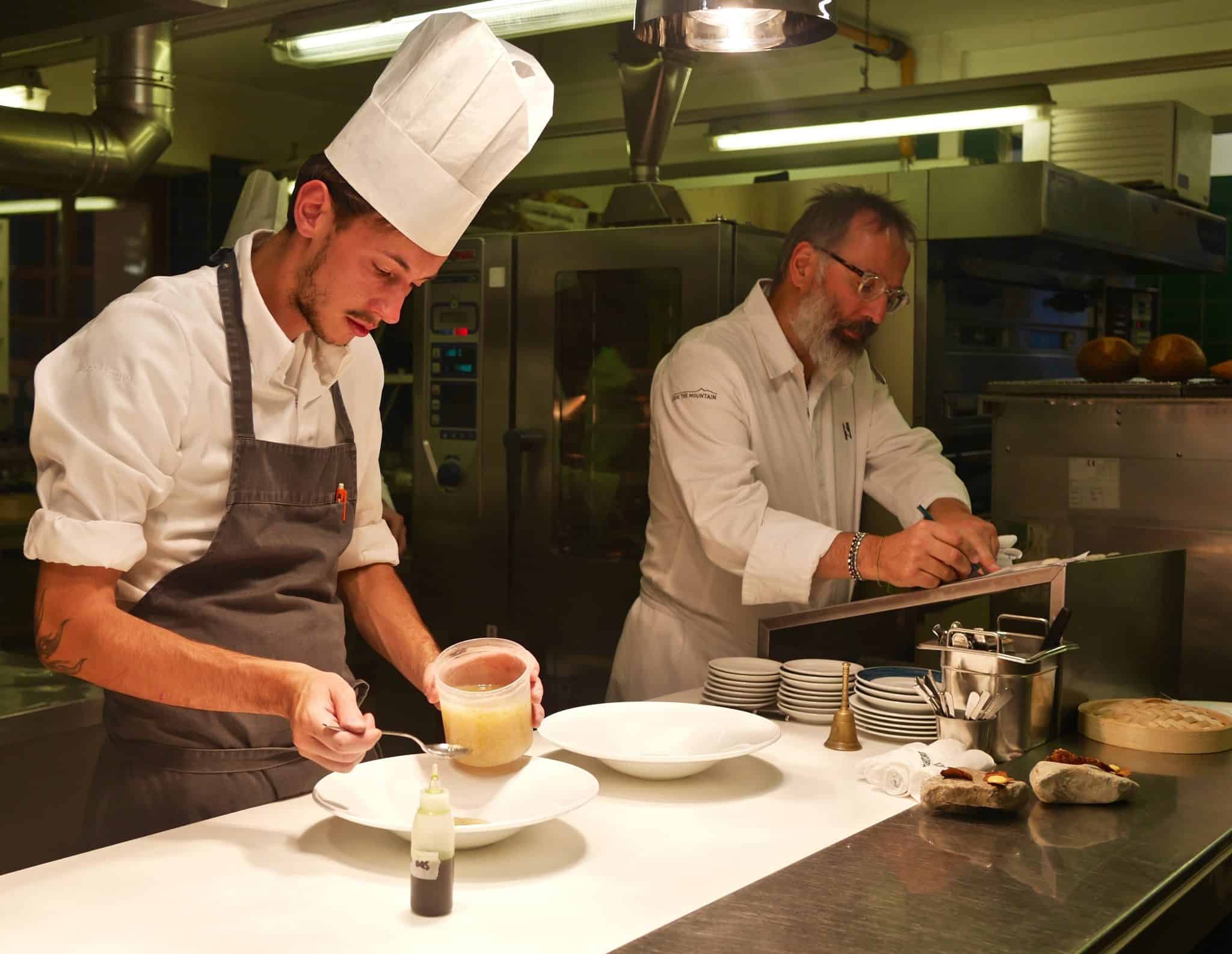 chefs in the kitchen one with a hat and grey apron other in white overall and glasses (Chef Norbert)