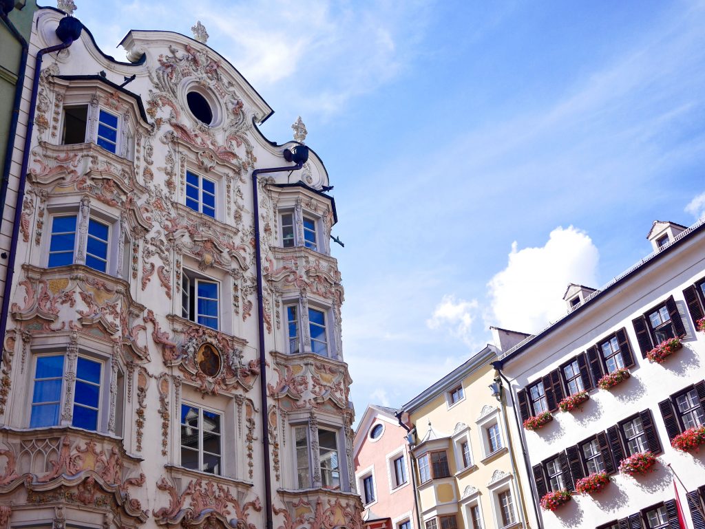 building with white and light pink architecture looking up to the sky along side the Goldenes Dachl 