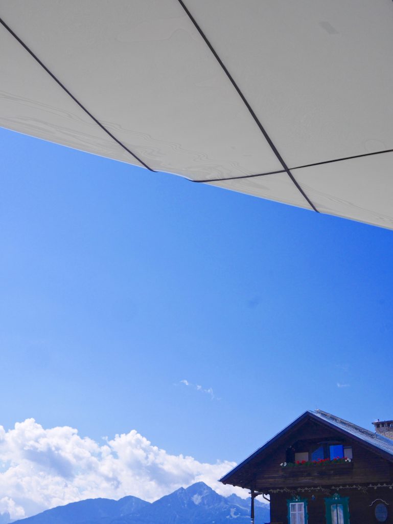 looking up at the blue sky that turns the mountains also blue with wooden chalet