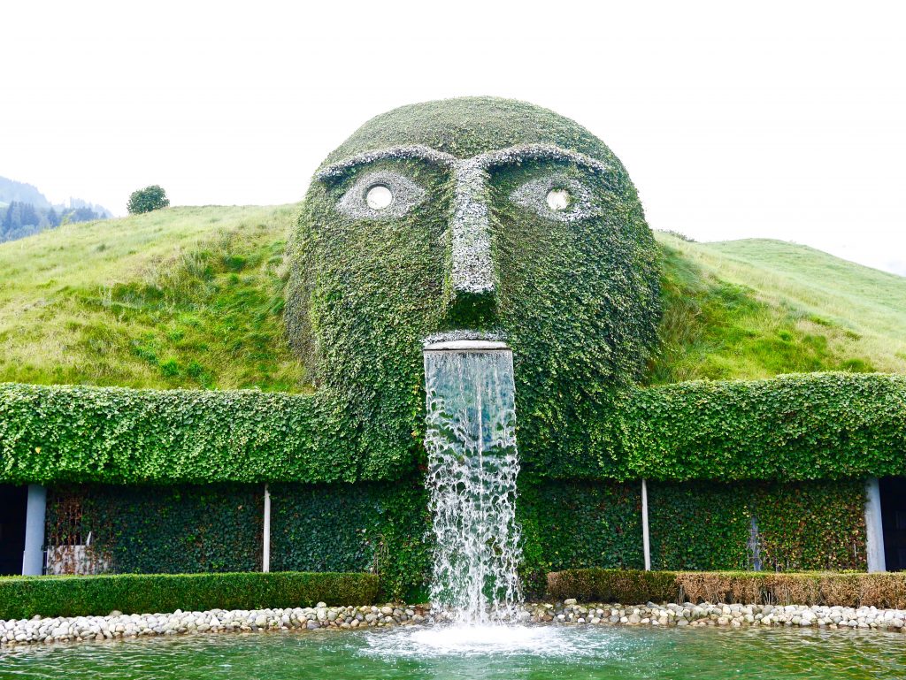 giants face in a manmade hill spouting a waterfall