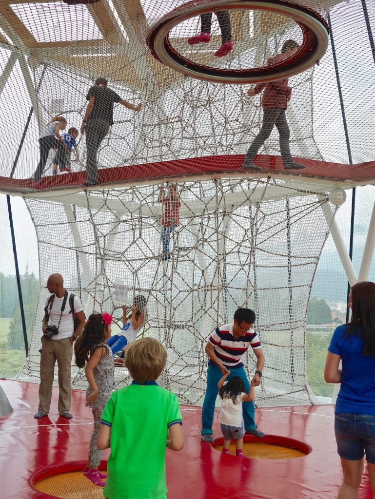 inside the tall glass play tower with ropes and nets for children and parents to climb