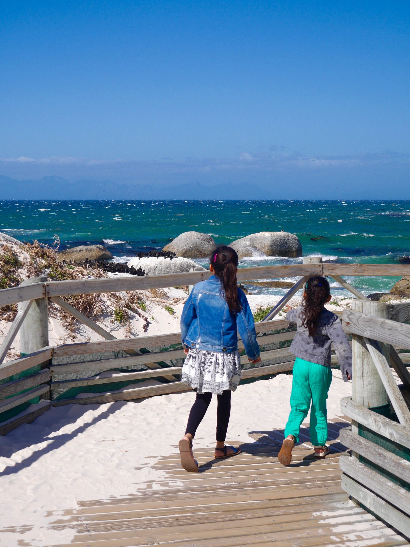 two girls on a pier looking out to sea