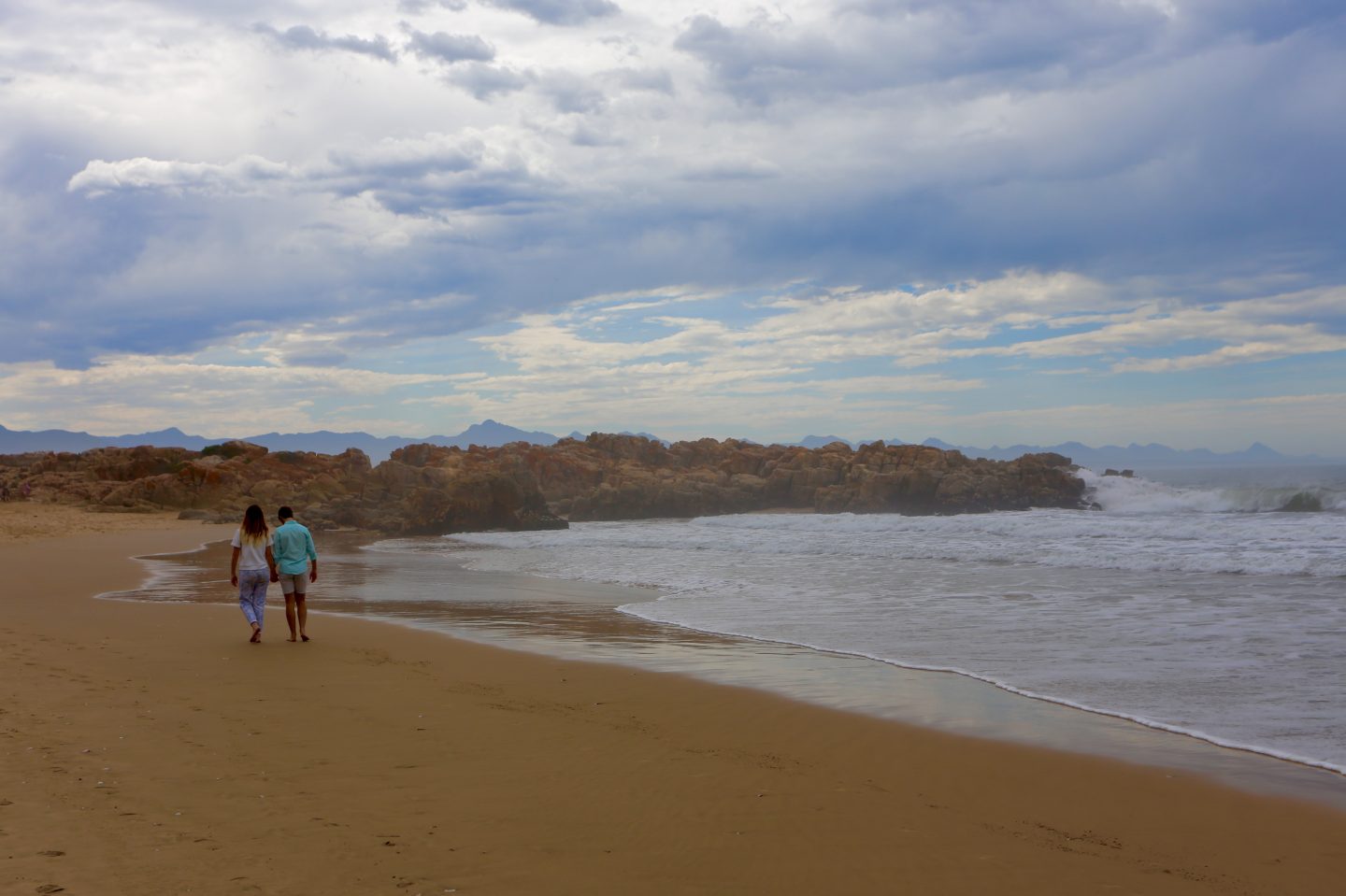 picture of man and woman walking away from the camera on the beach of Plettenberg Bay.
