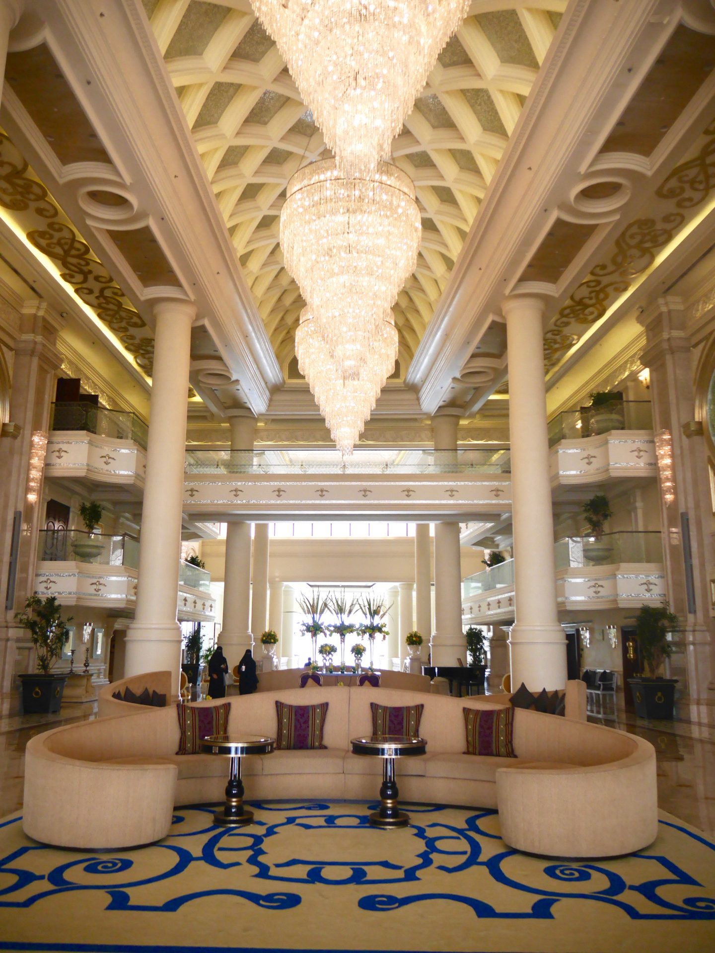 View of the inside of Ritz-Carlton Abu Dhabi Grand Canal with glass balconies, curved sofas and white chandeliers 