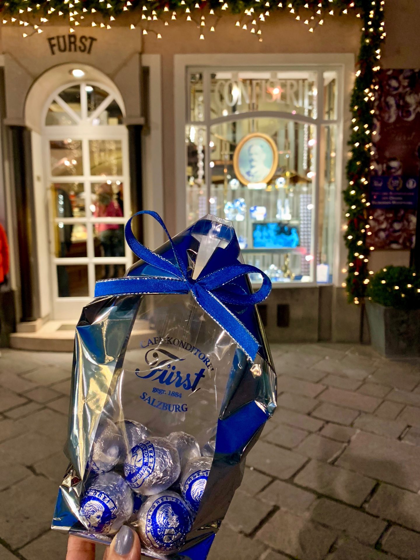 sima holding bag of blue Mozart chocolates in front of furst shop