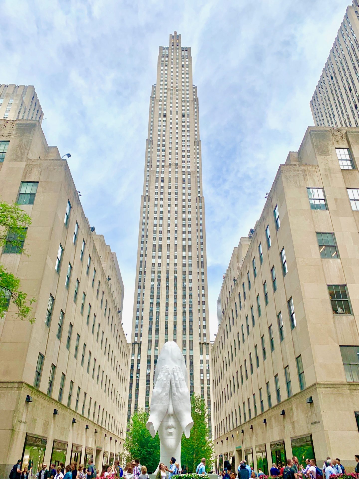 view of the Rockefeller Plaza looking up from the bottom with a white face statue with hands covering eyes
