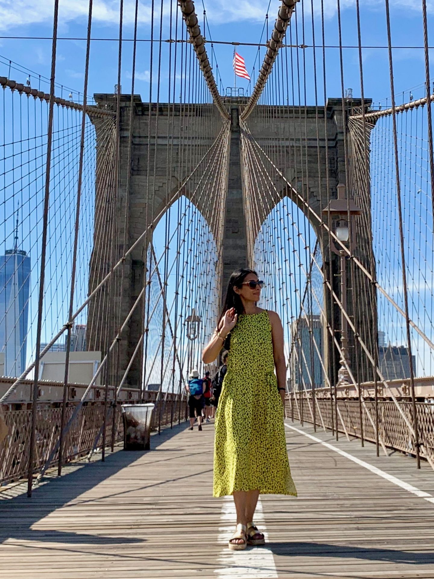sima in green dress walking Brooklyn Bridge
