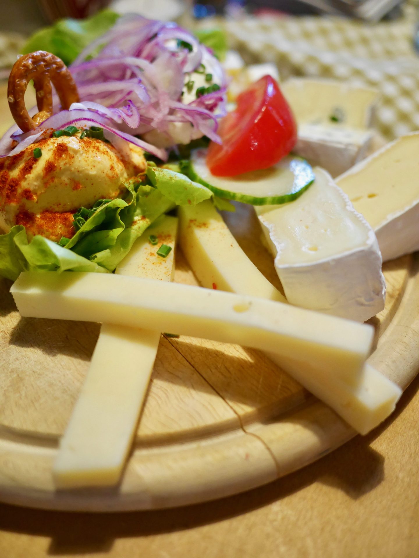 A cheese platter with a Bavarian cheese delicacy Obazda and a Kartoffeltaschen, a potato pocket filled with cream cheese and served on a salad.