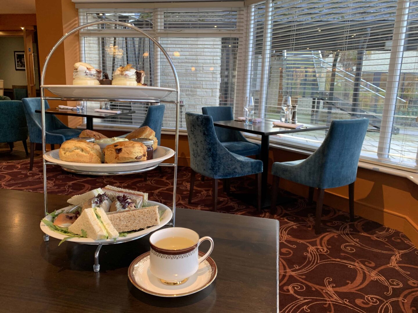 scones, cakes and finger sandwiches alongside a cup of tea