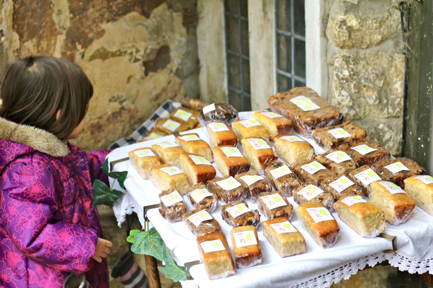 child looking at the baked goods wrapped up on a table outside the tearoom in The Cotswolds