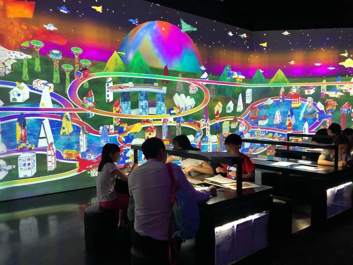 view of families at tables along side brightly coloured art designs on wall 