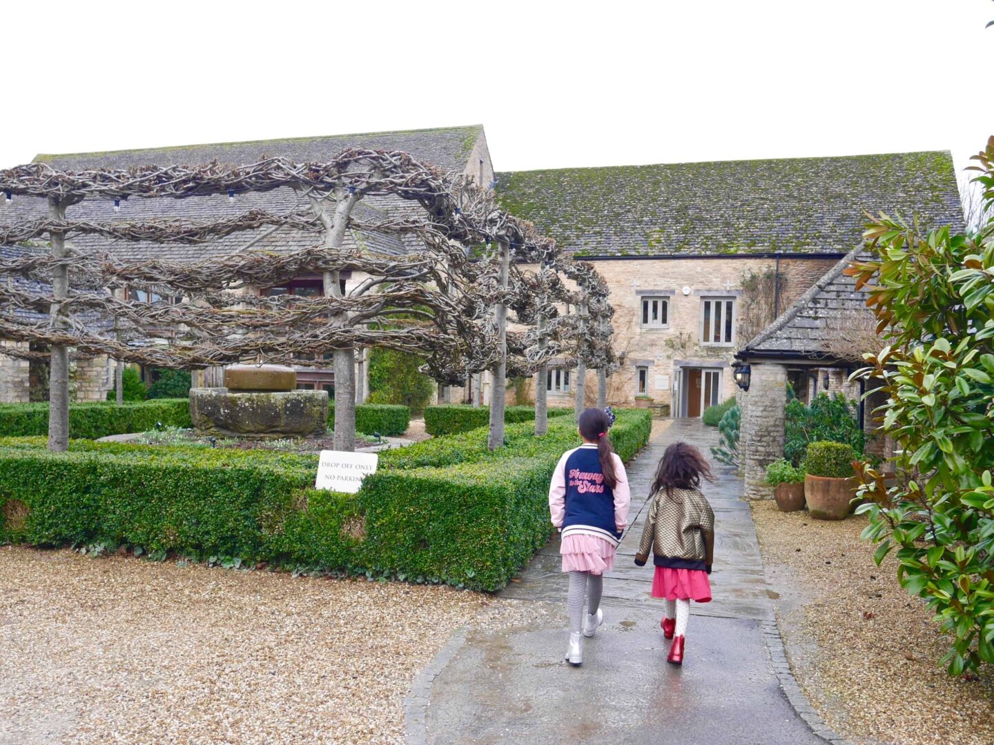 image of two girls walking on a path towards the entrance of the Calcot manor