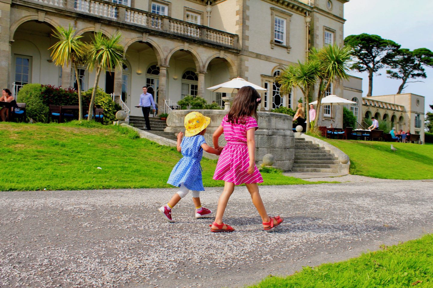 image of two girls in blue and pink dress holding hands in front of a luxury hotel