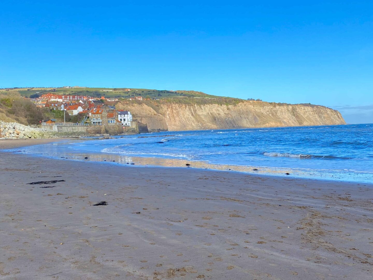 view of Whitby from the beach looking up at a cliff and cliff top houses