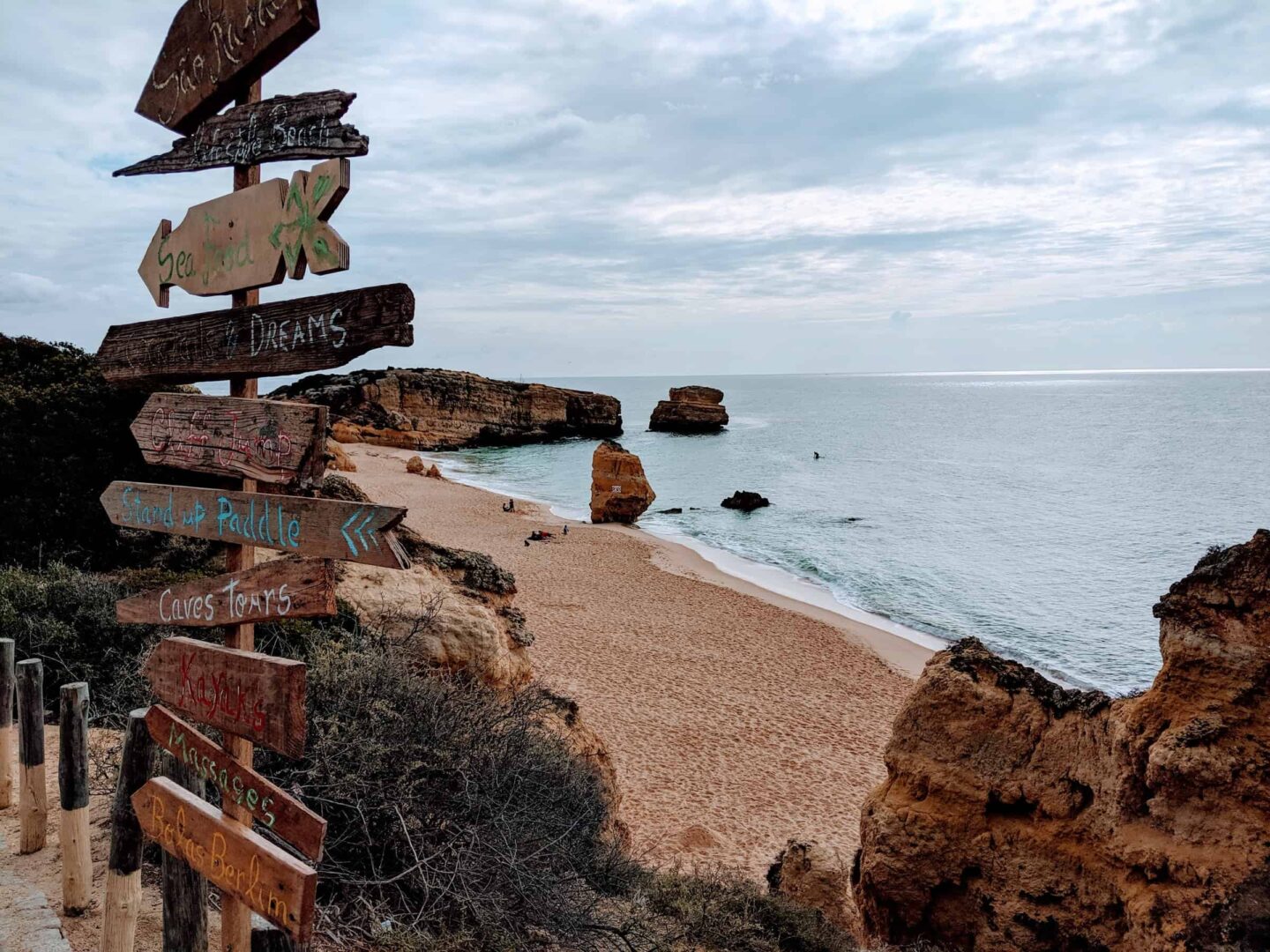 view of a wooden sign alongside the beach of the algarve
