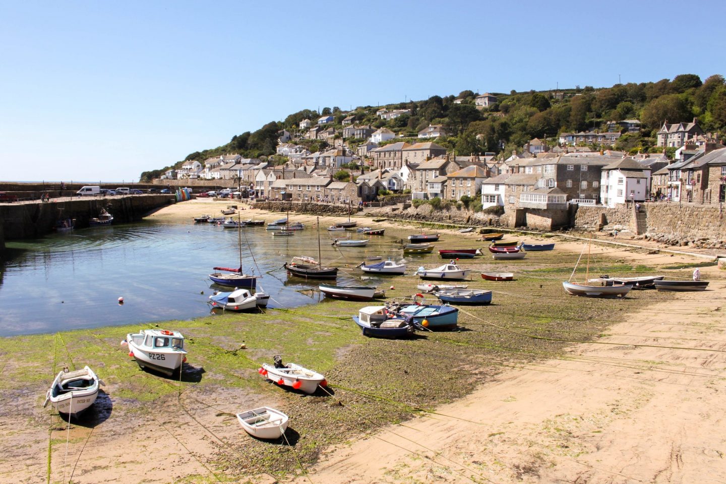 view of the low tide in st ives with boats moored on the sand surrounded by houses up the mountain side
