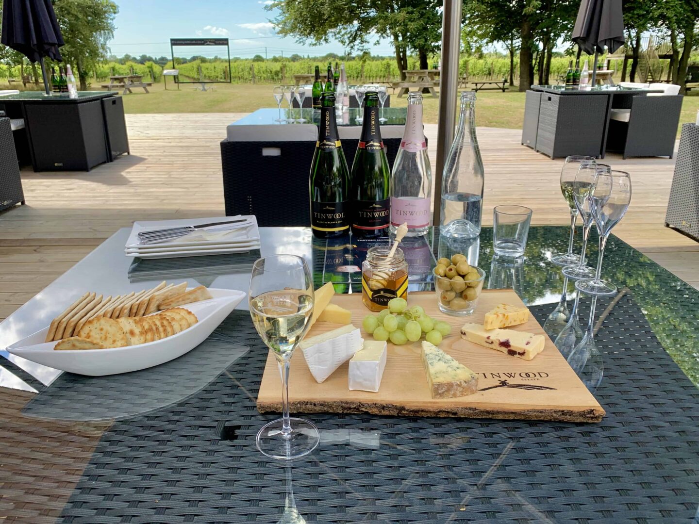 view of the cheeseboard, crackers and wine bottles & glasses at West Sussex vineyard at Tinwood Estate
