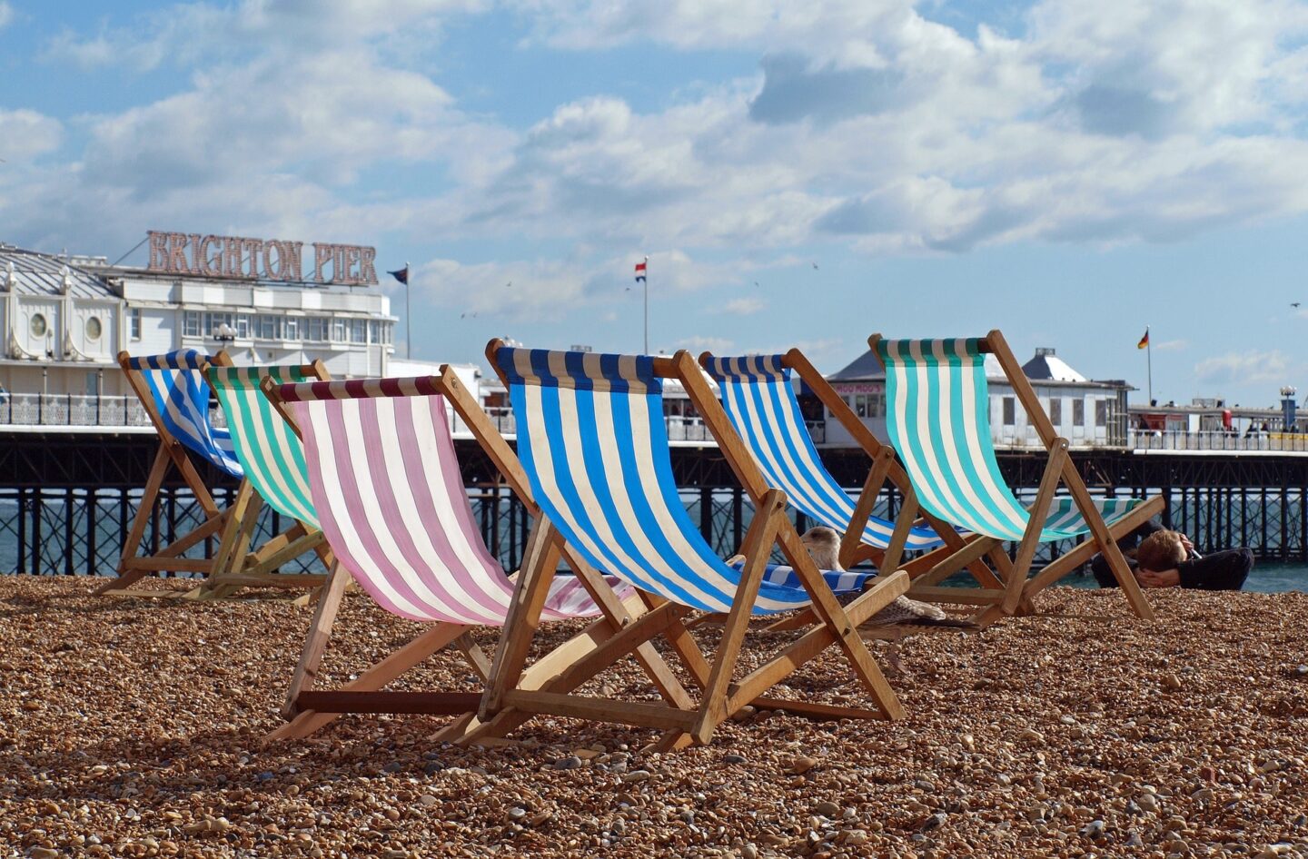 view of multi coloured deckchairs on the pebbled beach of Brighton beach at the side of Brighton pier