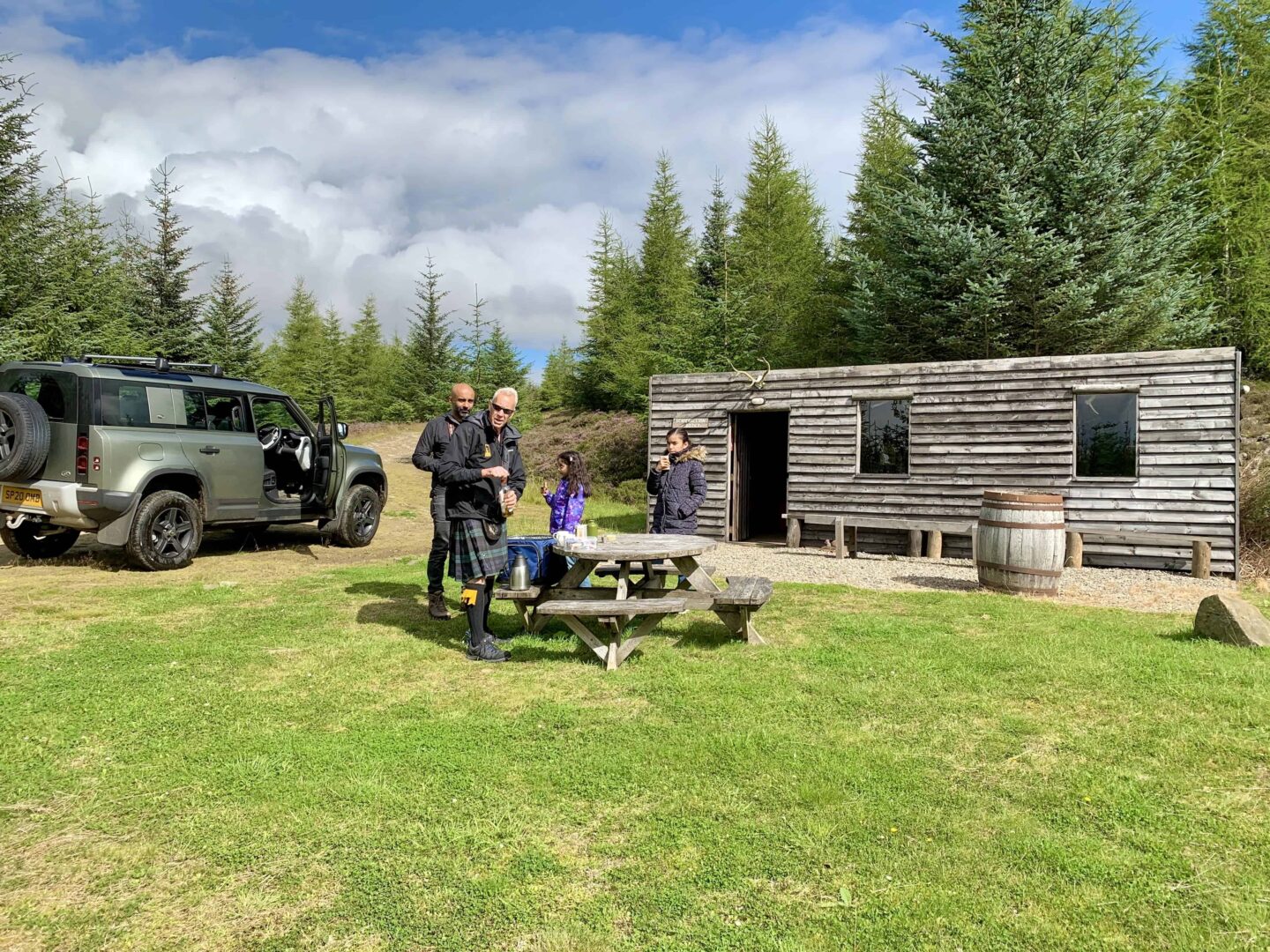 view of the cabin, 4x4 vehicle, father and two daughters plus the kilt wearing guide at highlands safari