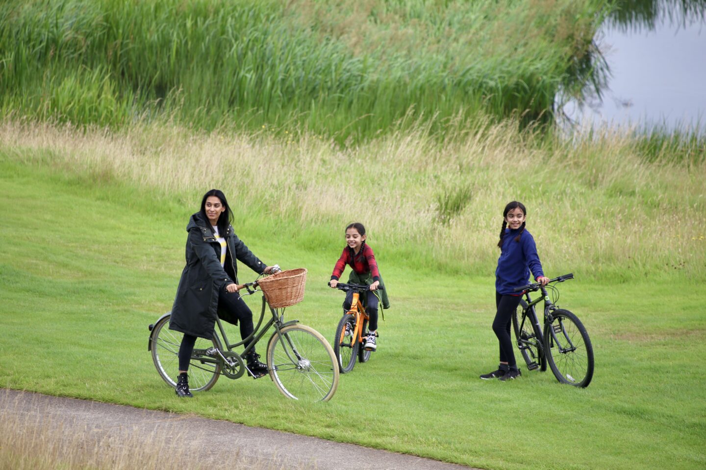 view of sima and two daughters on grass and bikes