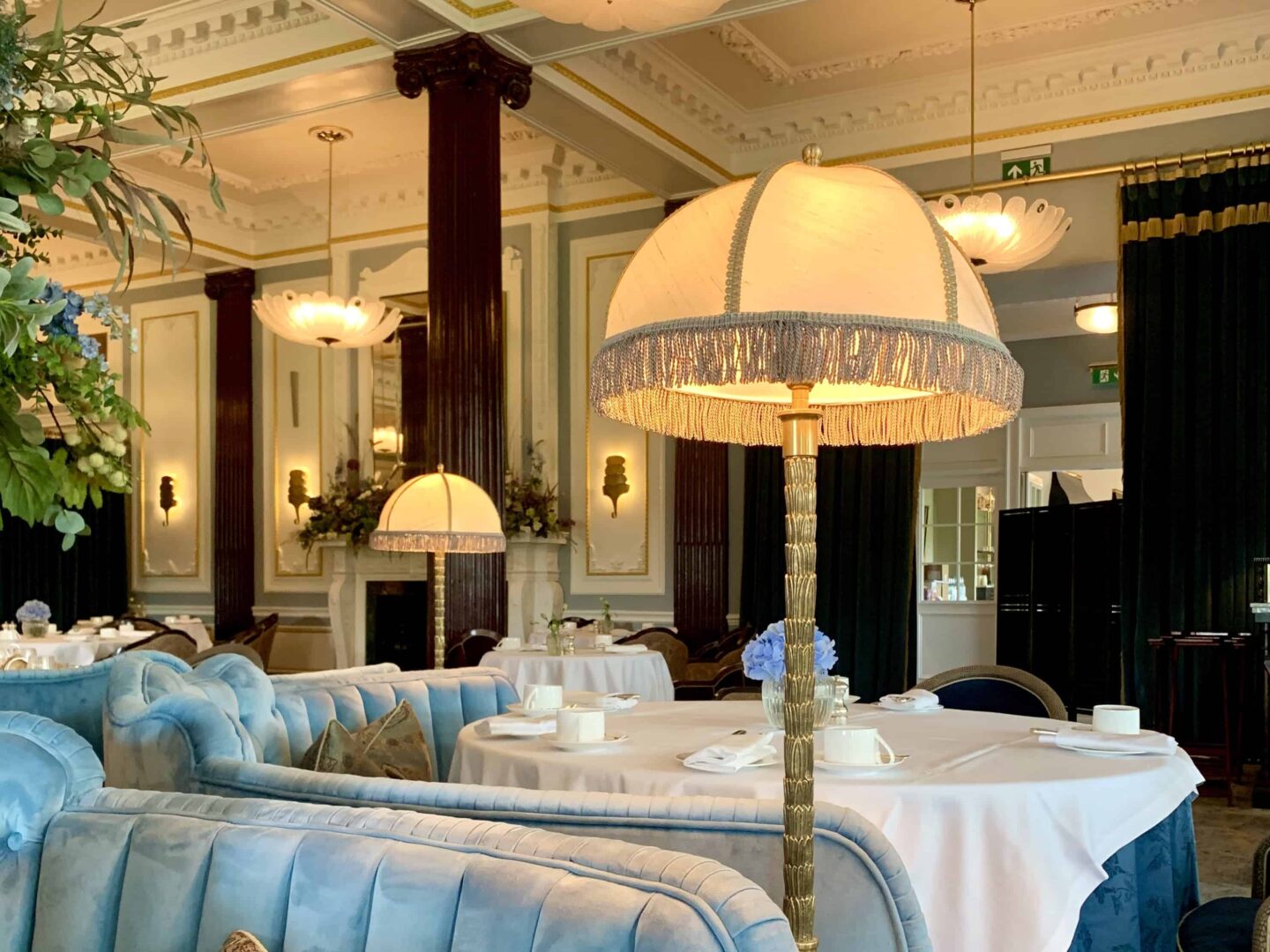 view inside the restaurant with dark wooden beams, blue velvet sofa style chairs and tall floor lamps