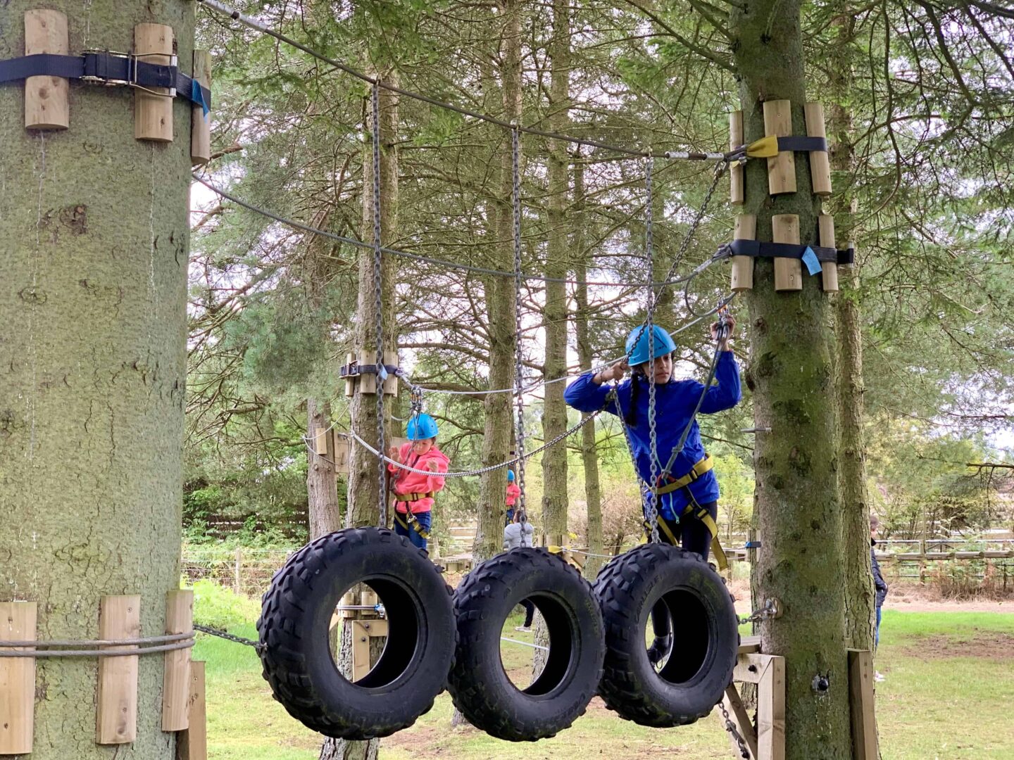 view of the children & sima on the outdoor climbing area wearing blue hard hats